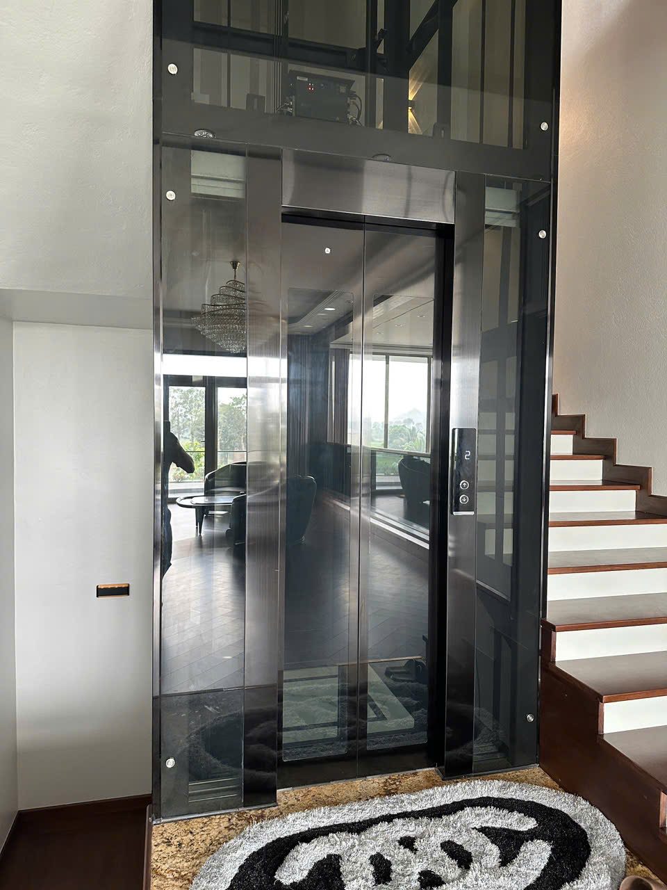 Thang máy kính cạnh cầu thang gỗ trong nhà ở — ảnh 1